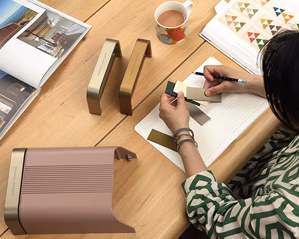 Une conceptrice travaille avec des échantillons de couleurs, du café et des magazines de design
