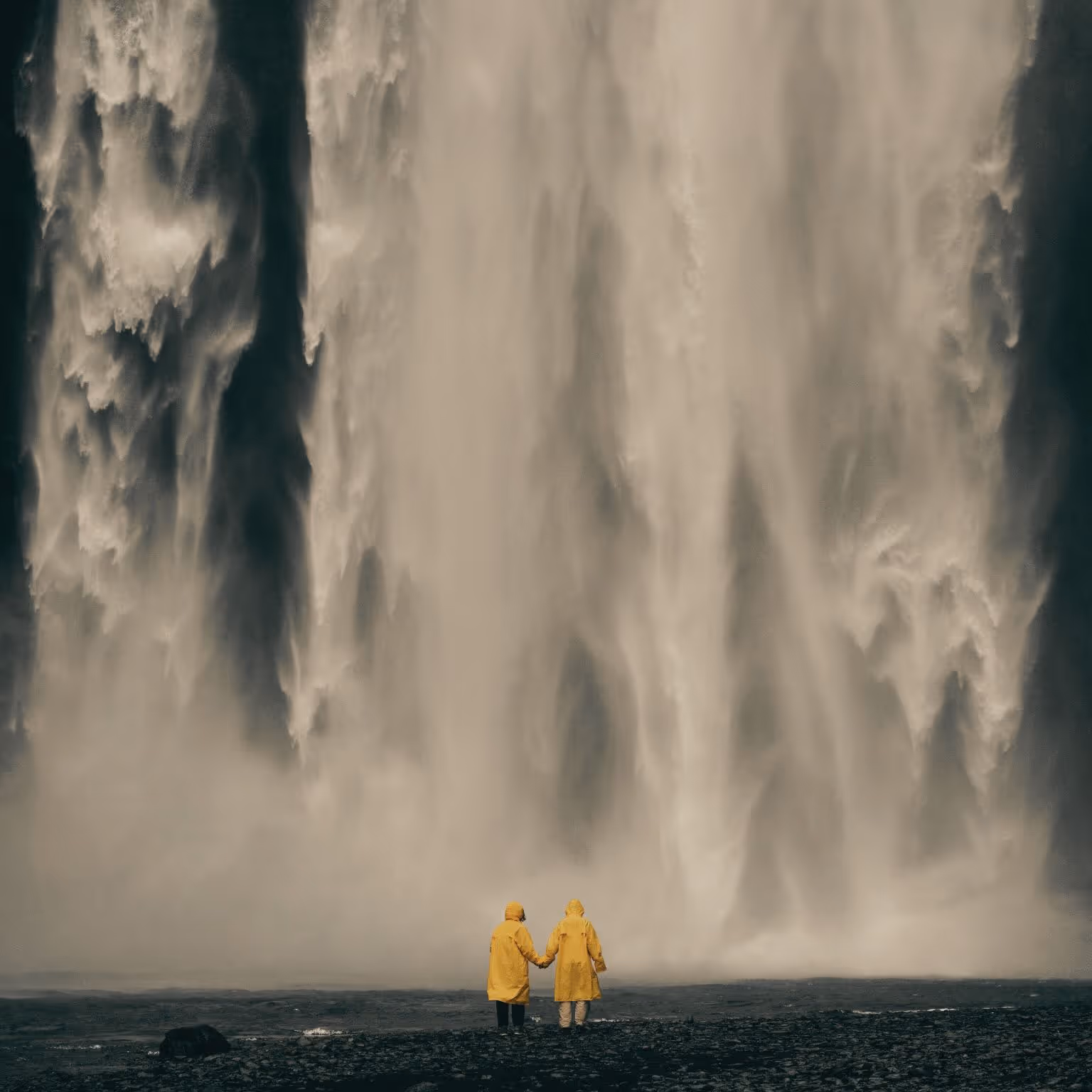 Das Bild zeigt zwei Personen mit Regenmänteln vor einem Wasserfall. Dennis ist Dein Regenmantel zum Schutz vor Wasser, stellvertretend für Fragen und Probleme die auftreten während der Zusammenarbeit.