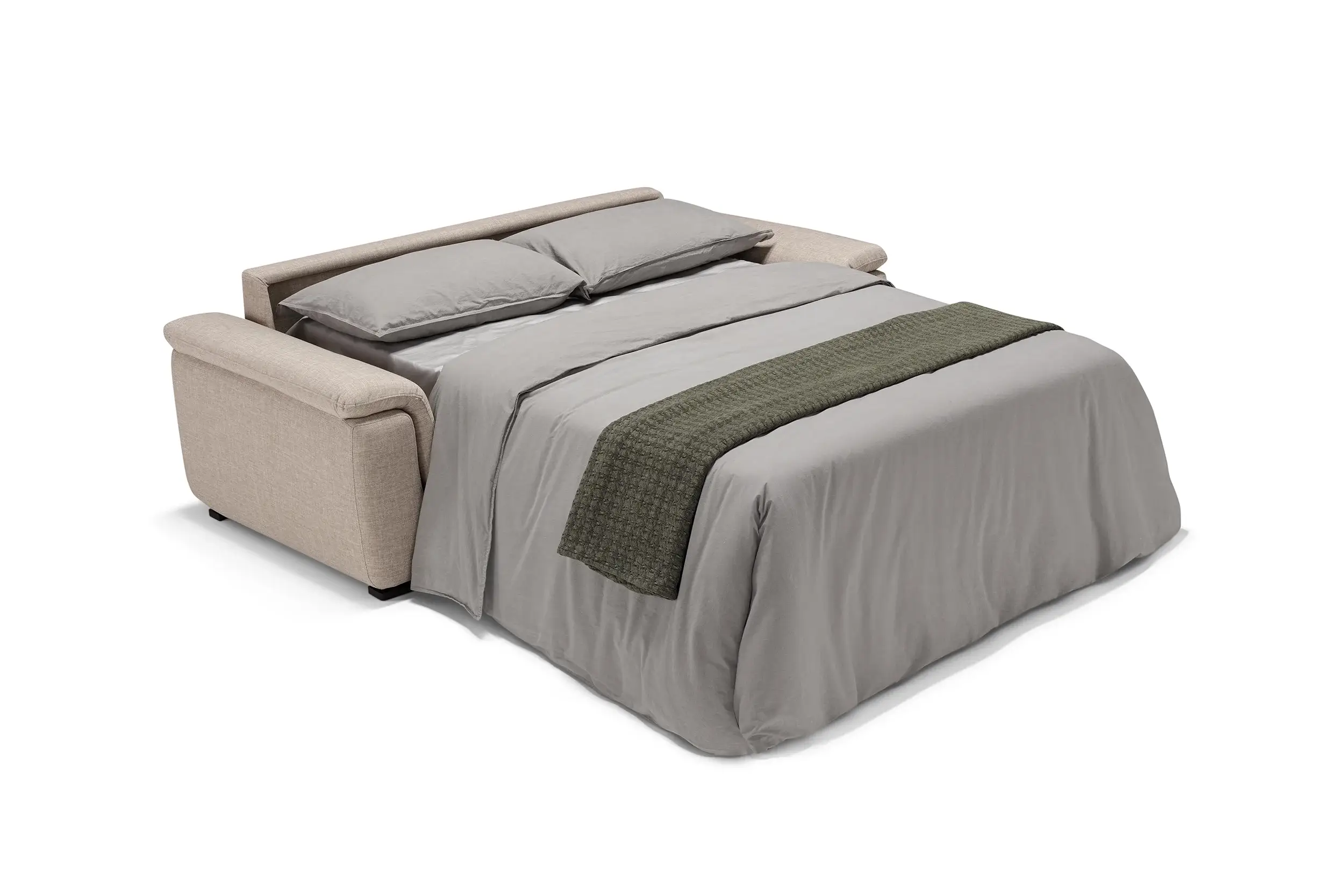 Beige fabric sofa bed unfolded and made up with gray bedding, two pillows, and a dark green textured runner.