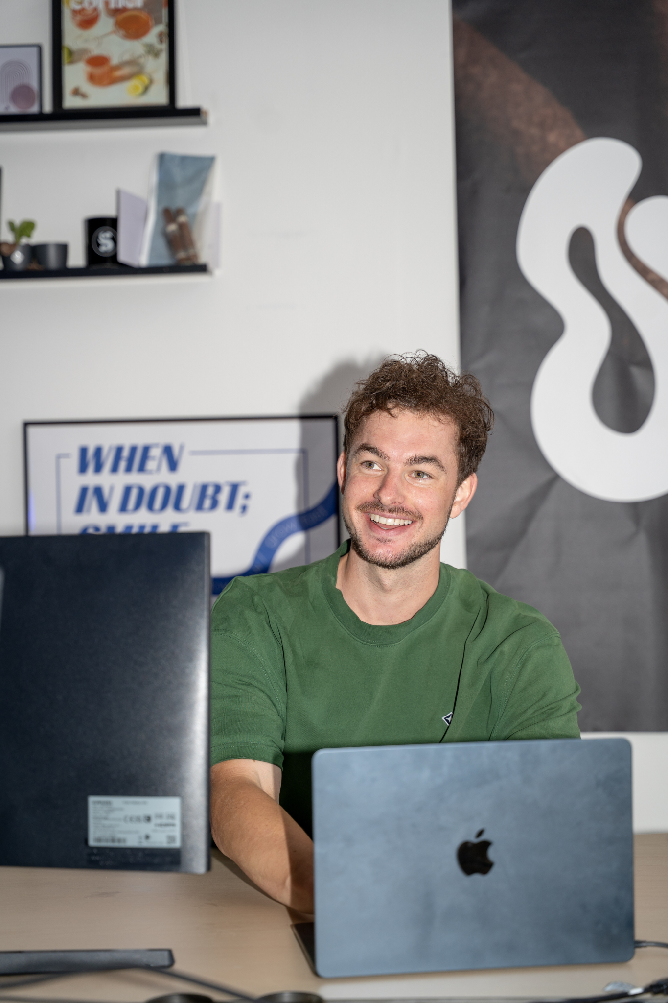 Lachende man achter laptop op kantoor.