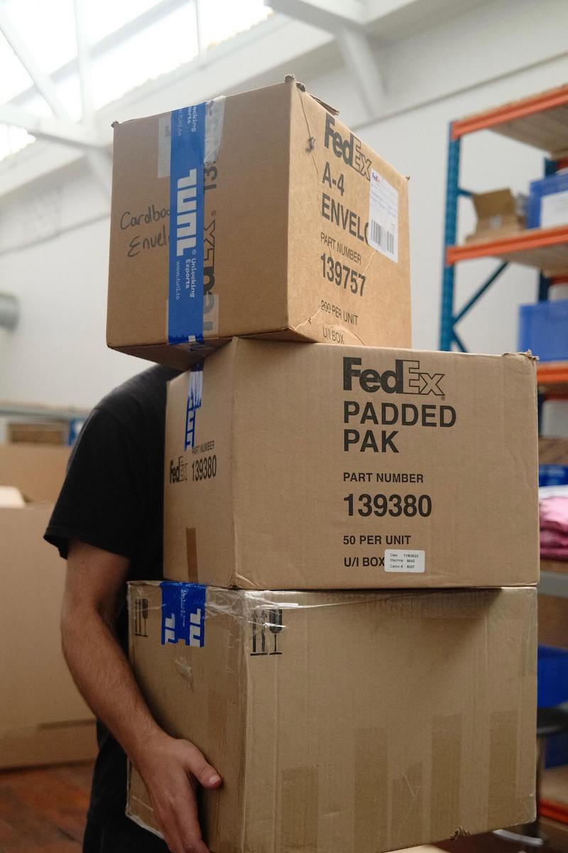 Stack of FedEx shipping boxes sealed with TUNL tape, showing affordable access to trusted international couriers