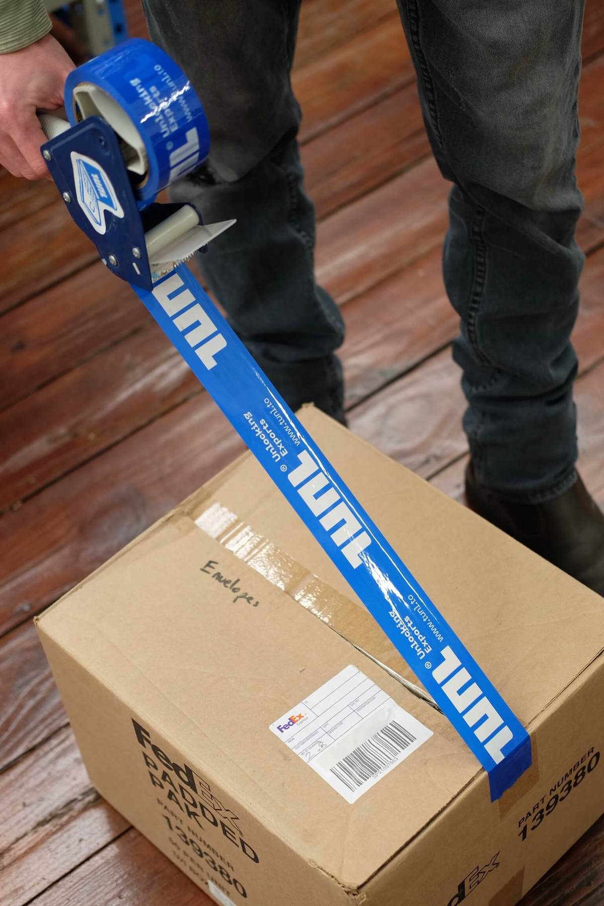 TUNL team member taping a box for international shipping