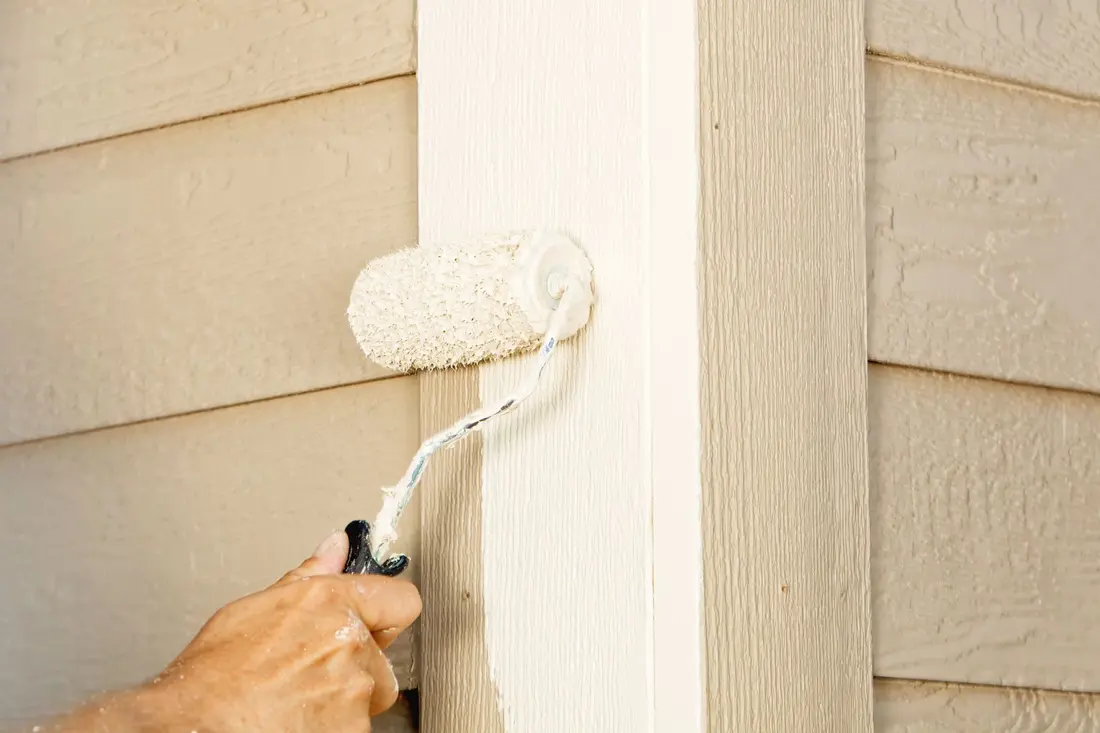 A person using a paint roller to paint a house
