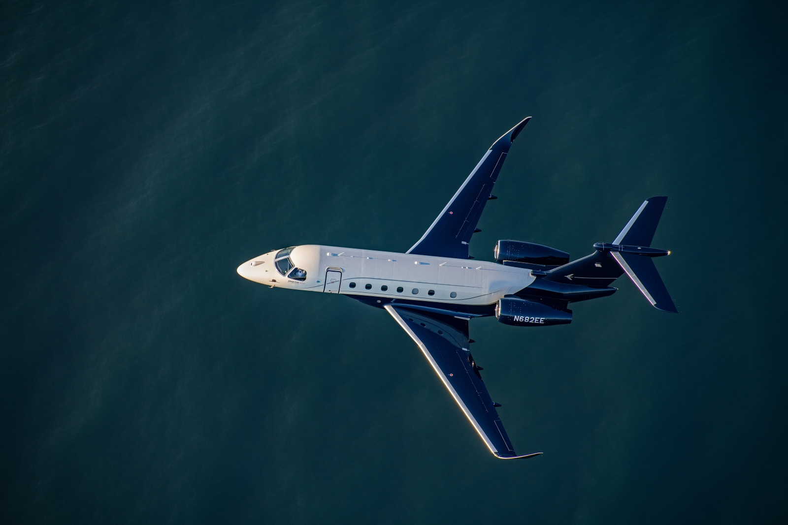 Embraer Praetor 600E super-midsize jet in flight above the ocean.
