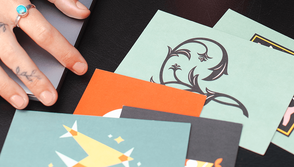 A close up of Alex Pesak, owner and Creative Director of AP the Creative, working at her laptop surrounded by typography postcards.