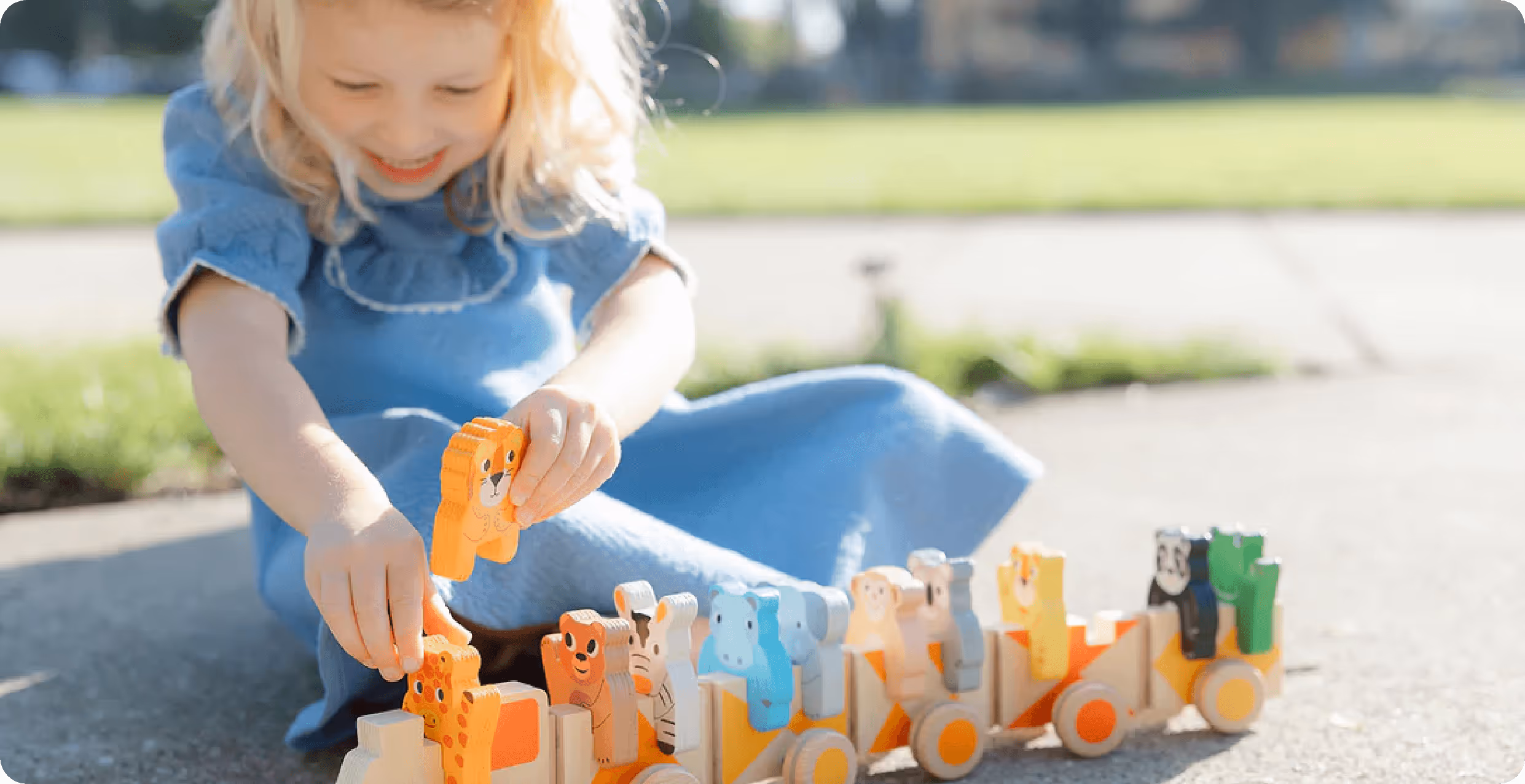 Goodies and Giggles Toy Store brand photography of little girl playing with a wooden train toy