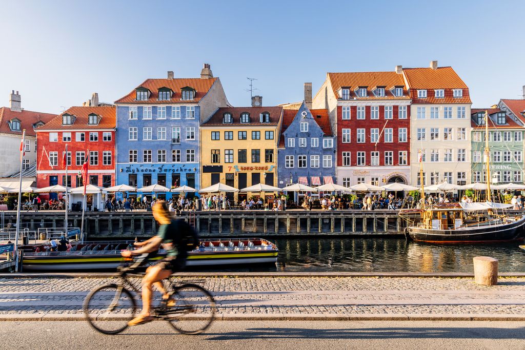 Nyhavn harbour with restaurants and crowds of tourists on a sunny summer day Copenhagen Denmark