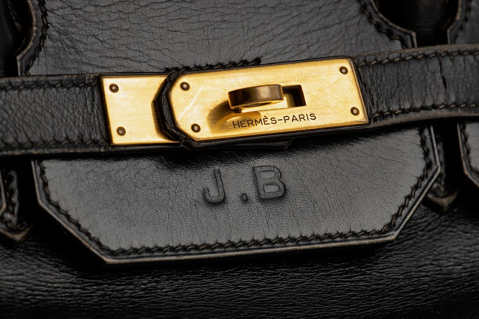 closeup of a black leather bag with a gold clasp and embossed initials
