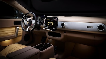 Vista del interior de un Ferrari Luce con volante, salpicadero beige y plata, pantalla central digital, y asientos claros. El nombre Luce es visible