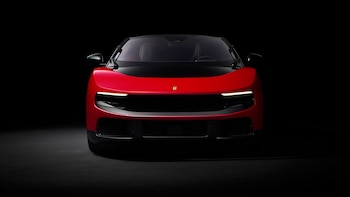 Vista frontal de un Ferrari Luce rojo brillante, una berlina de 4 puertas, con el techo oscuro y luces LED encendidas, sobre un fondo negro