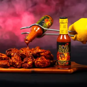 Hot Ones hot sauce beside a plate of chicken wings.