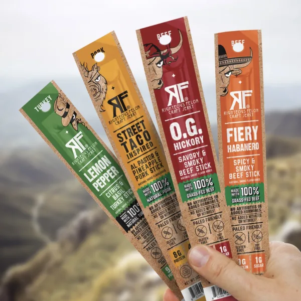 Hand holding four Righteous Felon craft jerky sticks: Lemon Pepper, Street Taco, O.G. Hickory and Fiery Habanero.