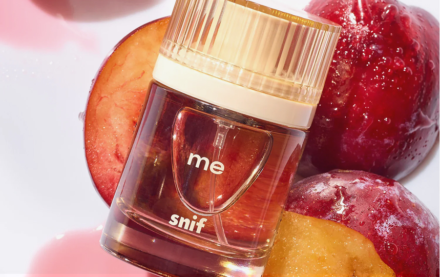Snif fragrance bottle beside fresh peaches.