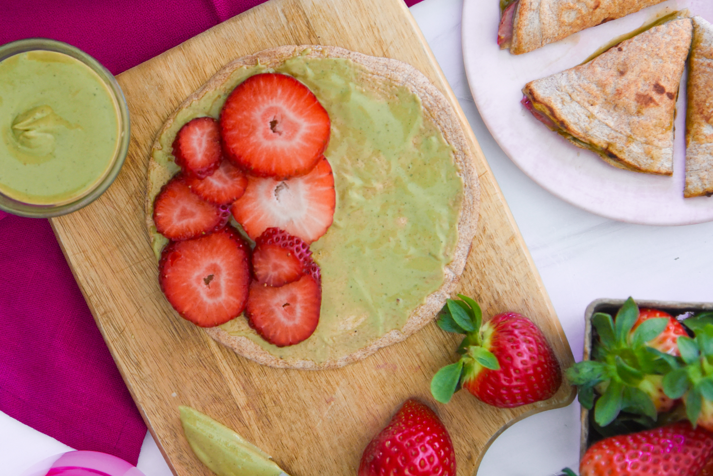 A close-up view of an Egglife wrap assembly, featuring pistachio butter spread and fresh strawberry slices.