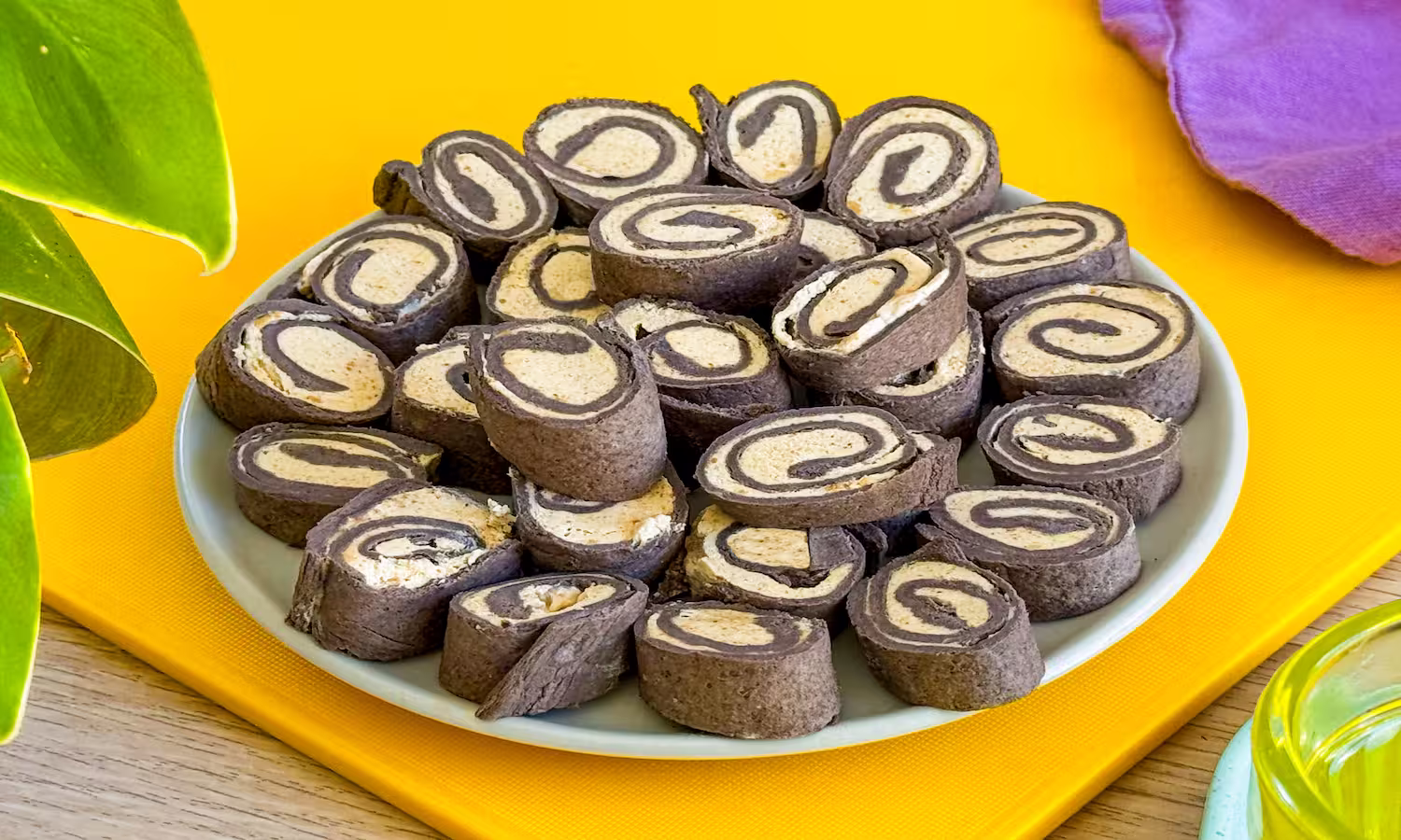 Chocolate egglife wraps ice cream bites rolled with a creamy peanut butter filling and sliced into bite-sized pinwheels on a plate.