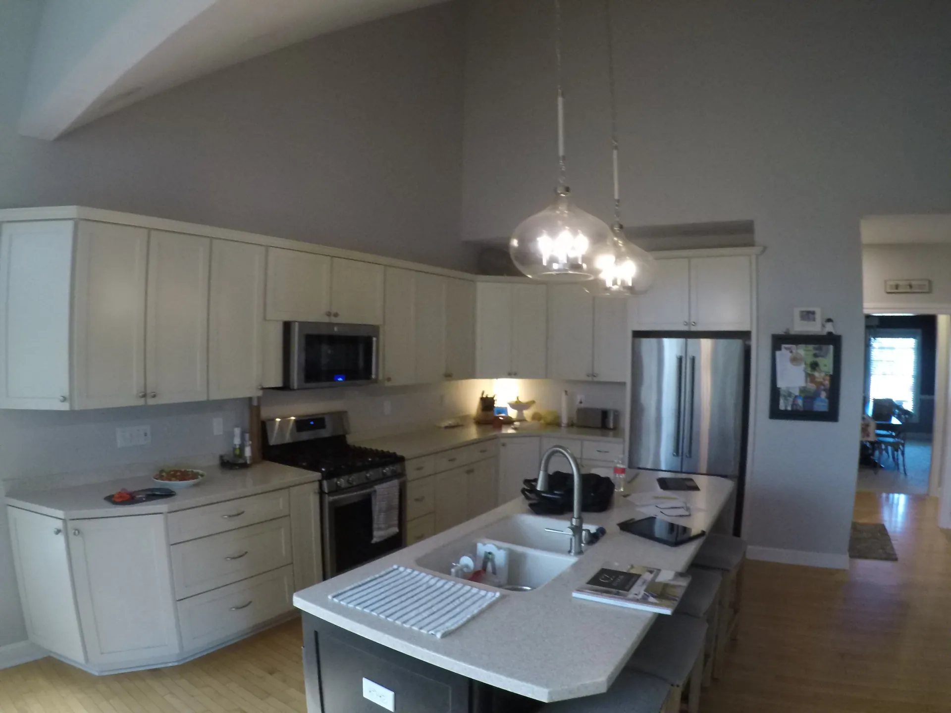 Kitchen before remodeling with white cabinetry, center island, stainless steel appliances, and vaulted ceiling.