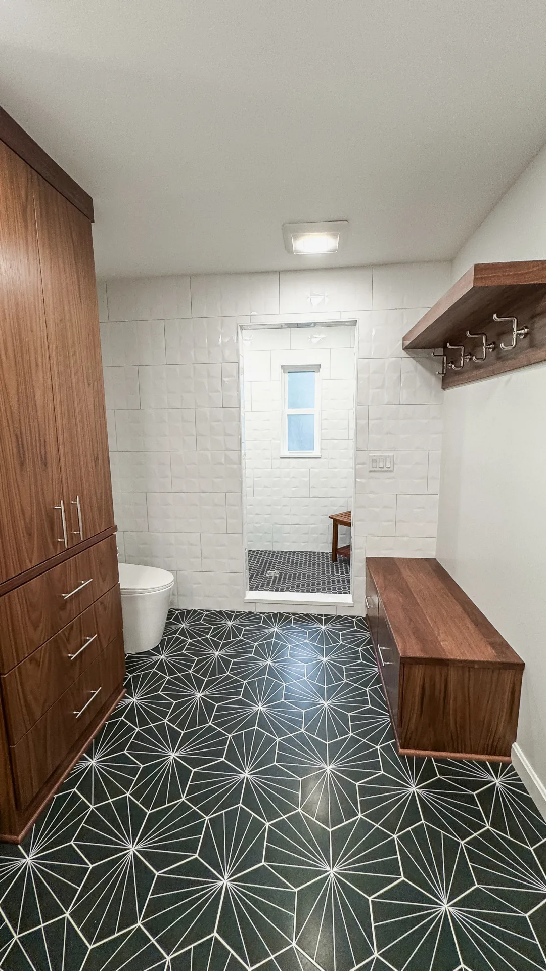 Custom walnut bathroom storage and walk-in tiled shower with built-in bench in a Wooster, Ohio bathroom remodel.