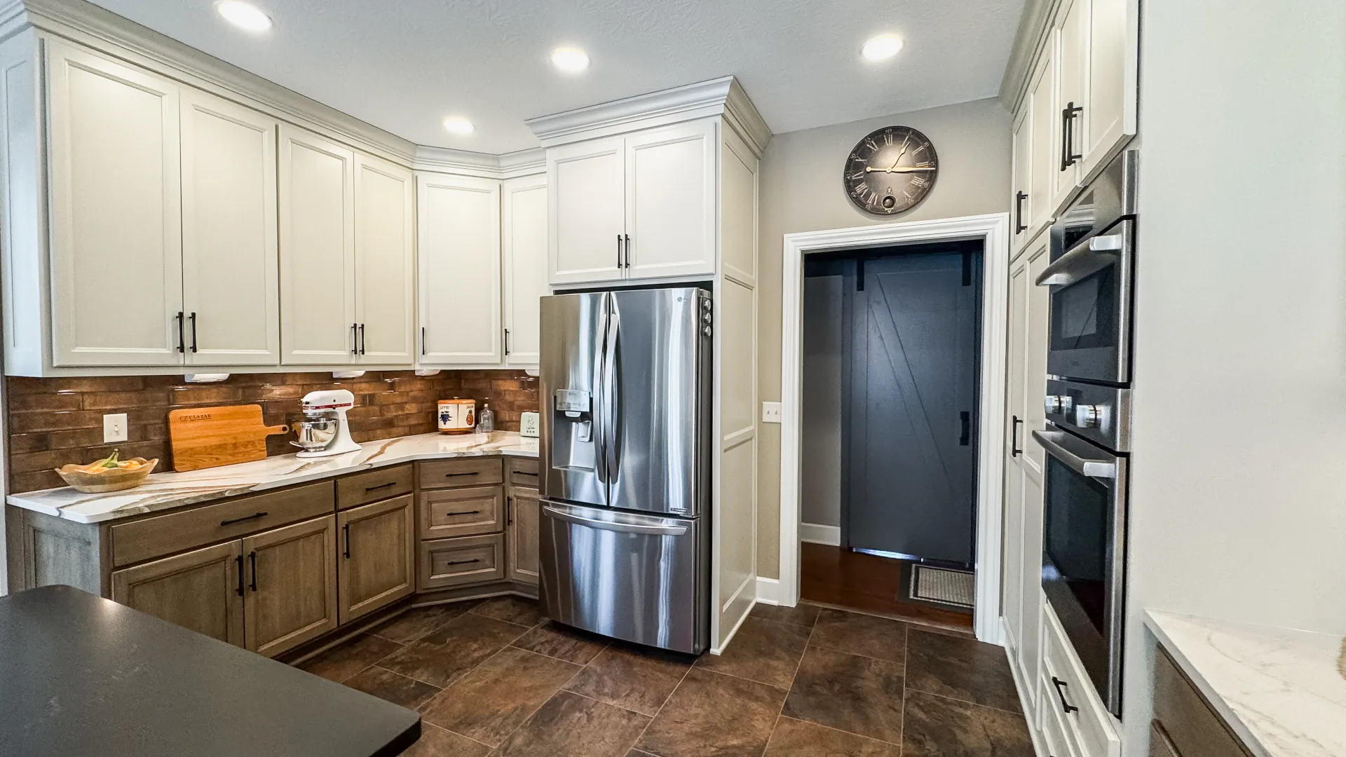 Remodeled Hinckley kitchen with white and wood cabinetry, quartz countertops, copper tile backsplash, and stainless steel appliances.