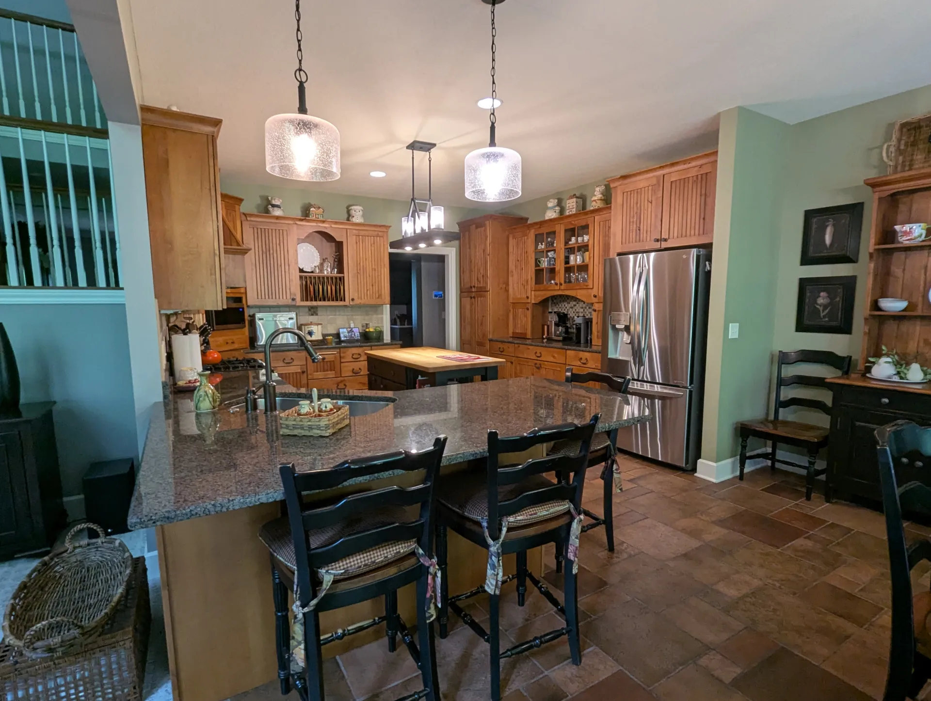 Kitchen before remodeling with wood cabinetry, granite peninsula, tile flooring, and an enclosed layout.