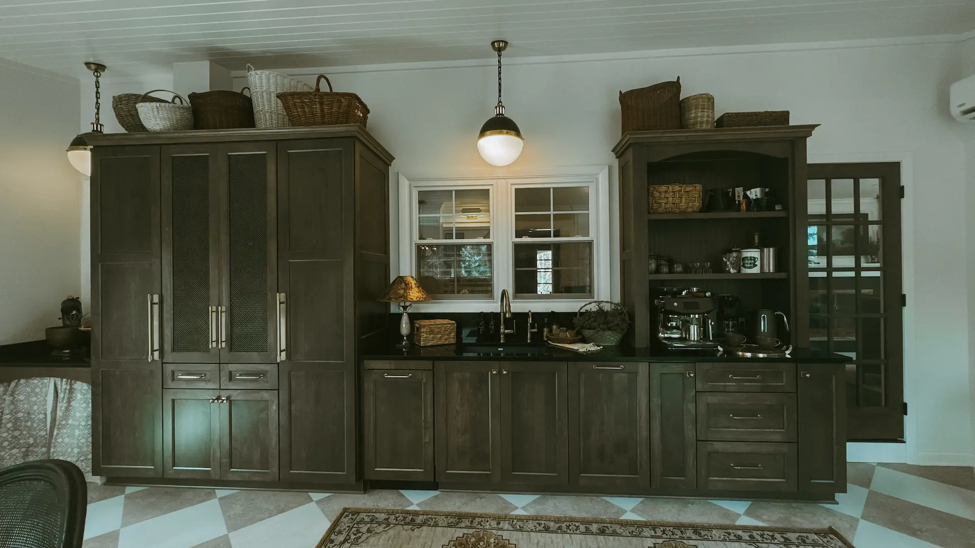 Custom butler’s pantry with dark furniture-style cabinetry, black countertops and open shelving