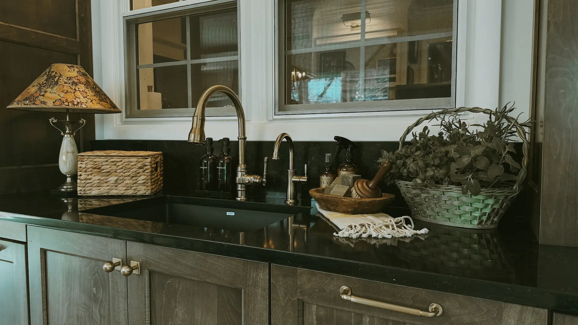 Butler’s pantry sink with dark custom cabinetry, black countertop and vintage-inspired accents