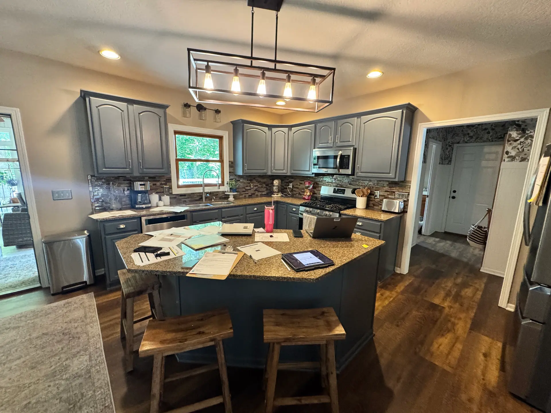 Kitchen before remodel with gray cabinetry, granite countertops and center island