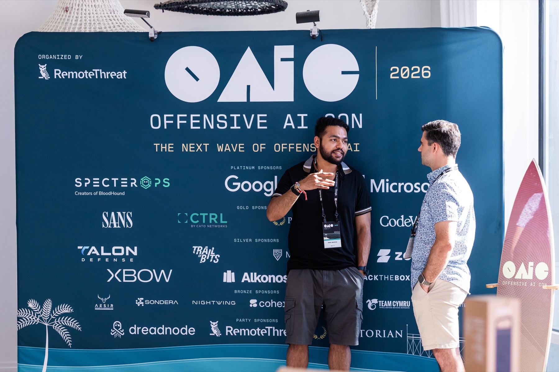 Attendees talking beside the OAIC 2026 sponsor backdrop