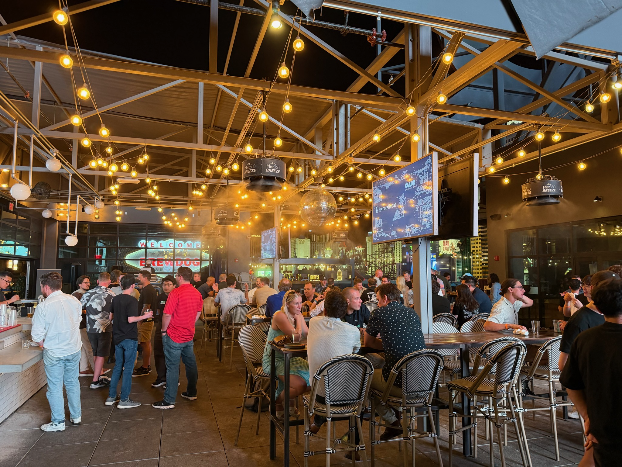 OAIC attendees in conversation beneath the rooftop string lights at Black Hat 2026