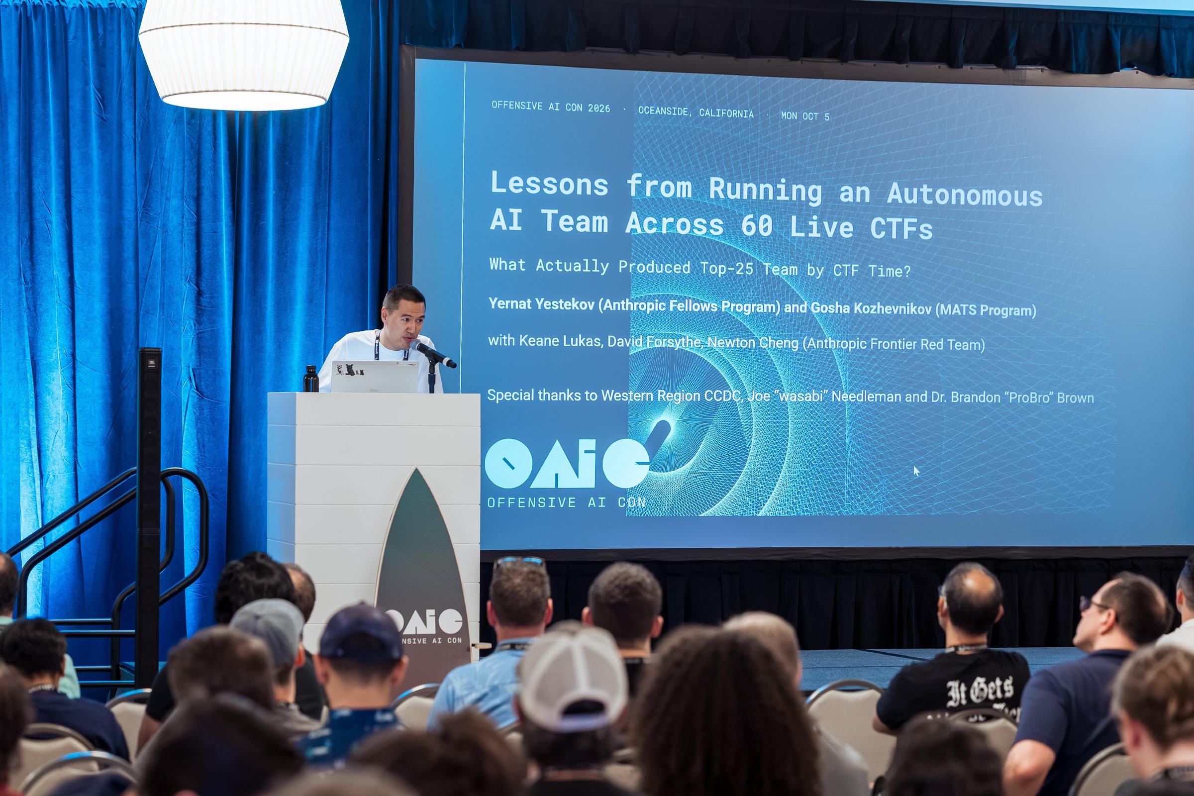 A researcher presenting lessons from an autonomous AI team on the main stage.