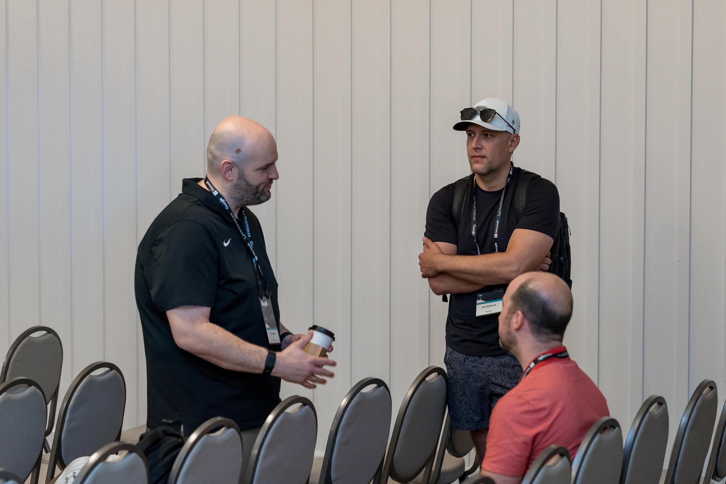 Attendees continuing a conversation near the conference room seating.