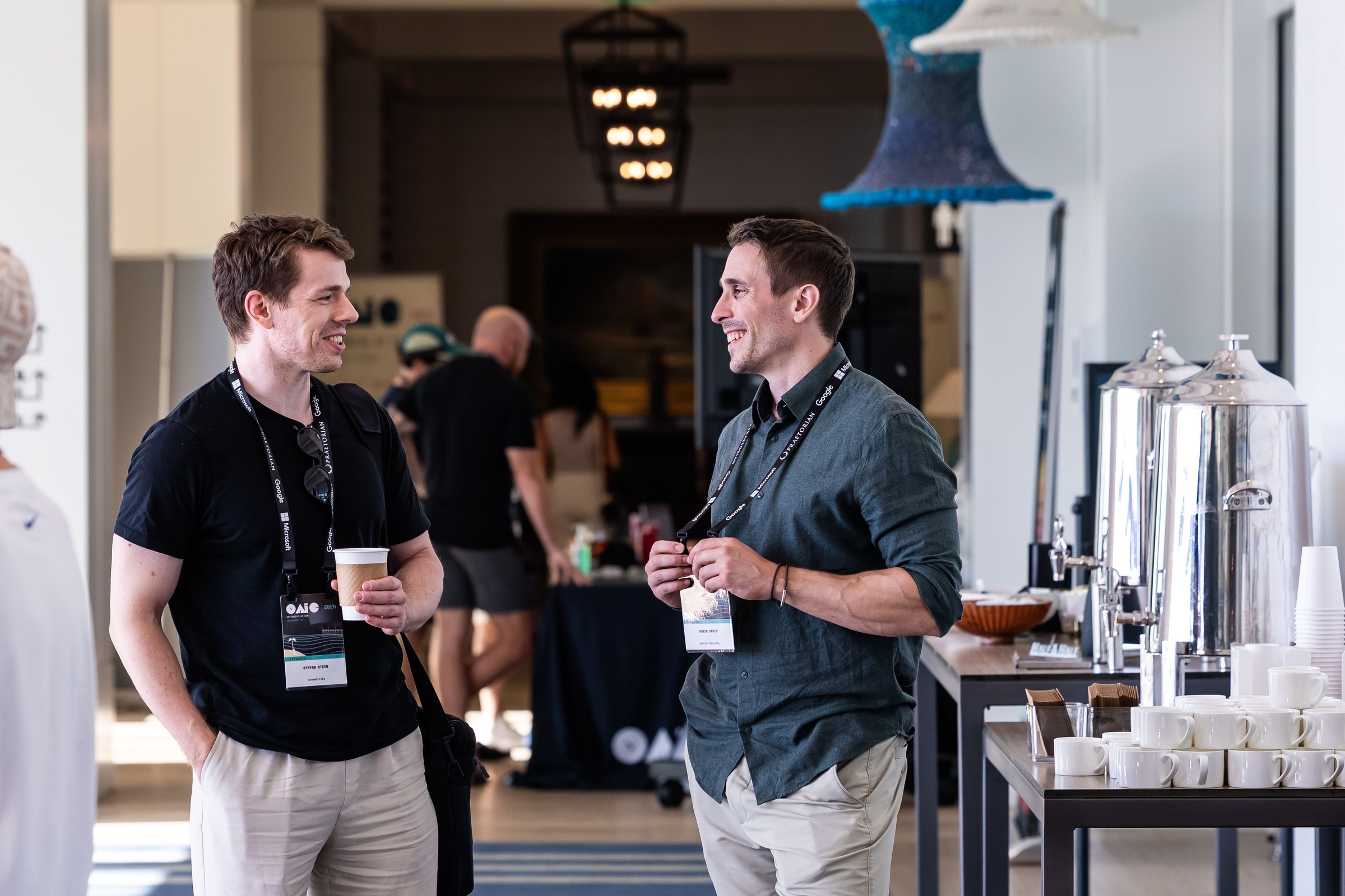 Two attendees talking beside the coffee station during a conference break.