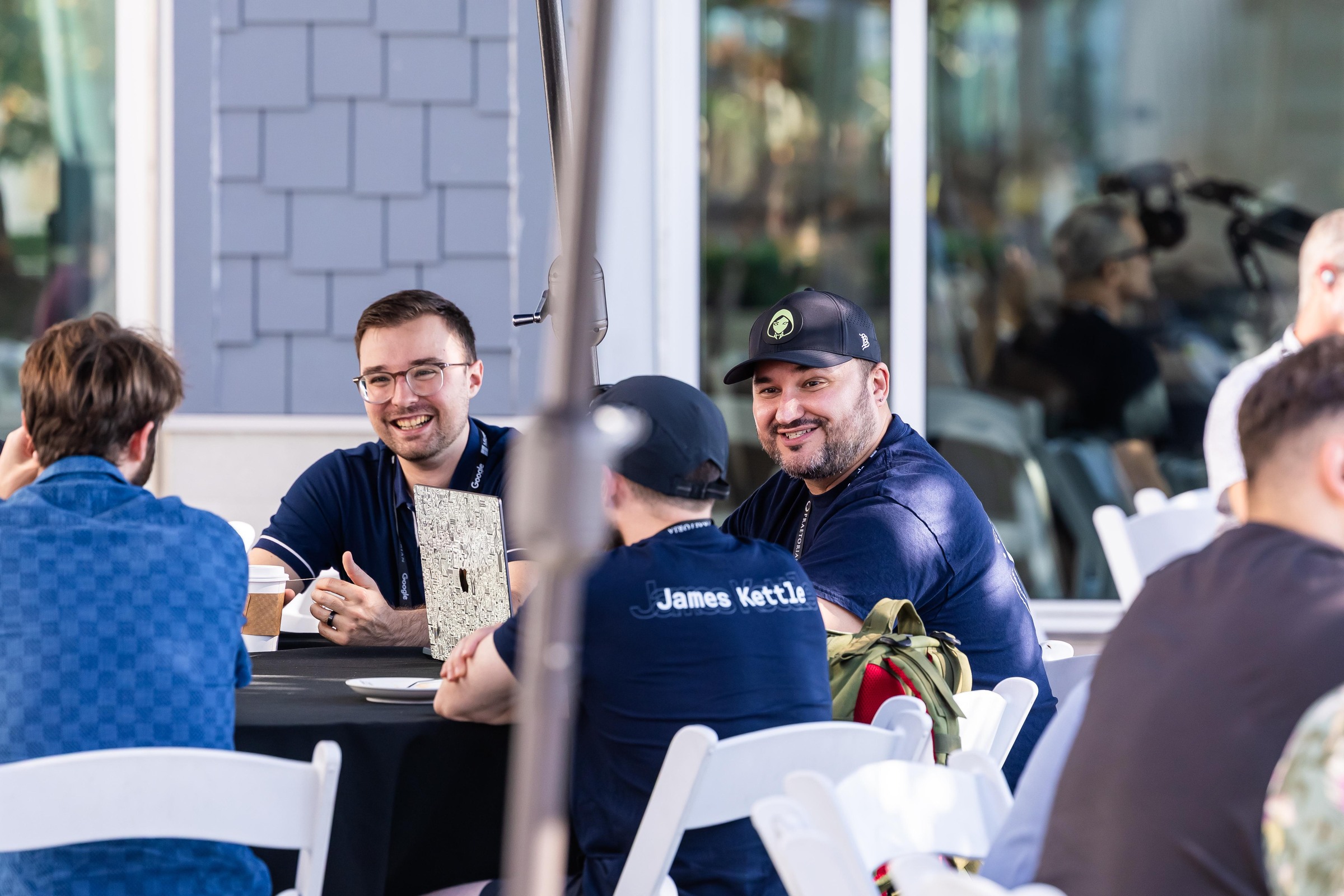 Attendees smiling and talking around a small table on the terrace.