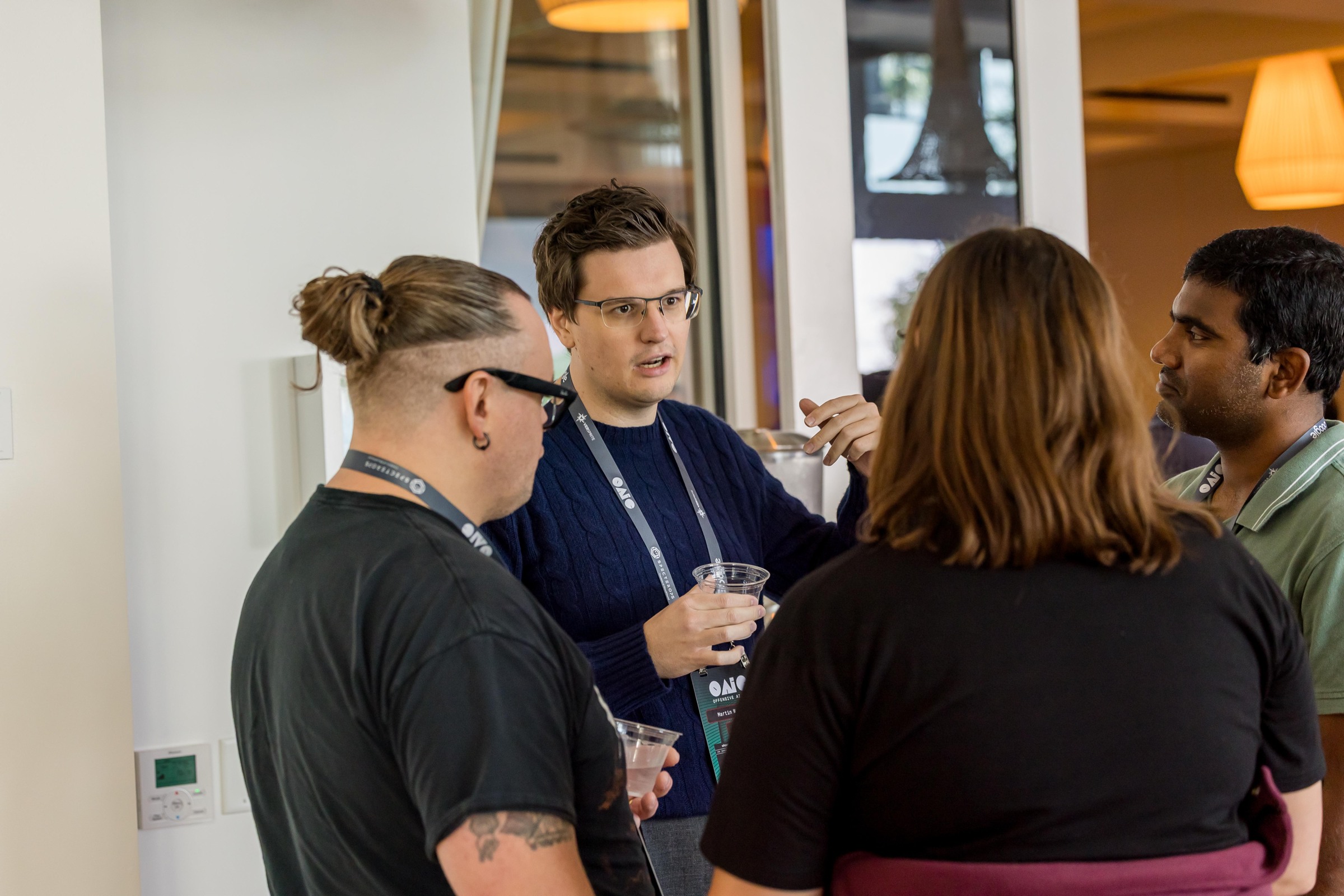 Four attendees exchanging ideas in the conference foyer between sessions.
