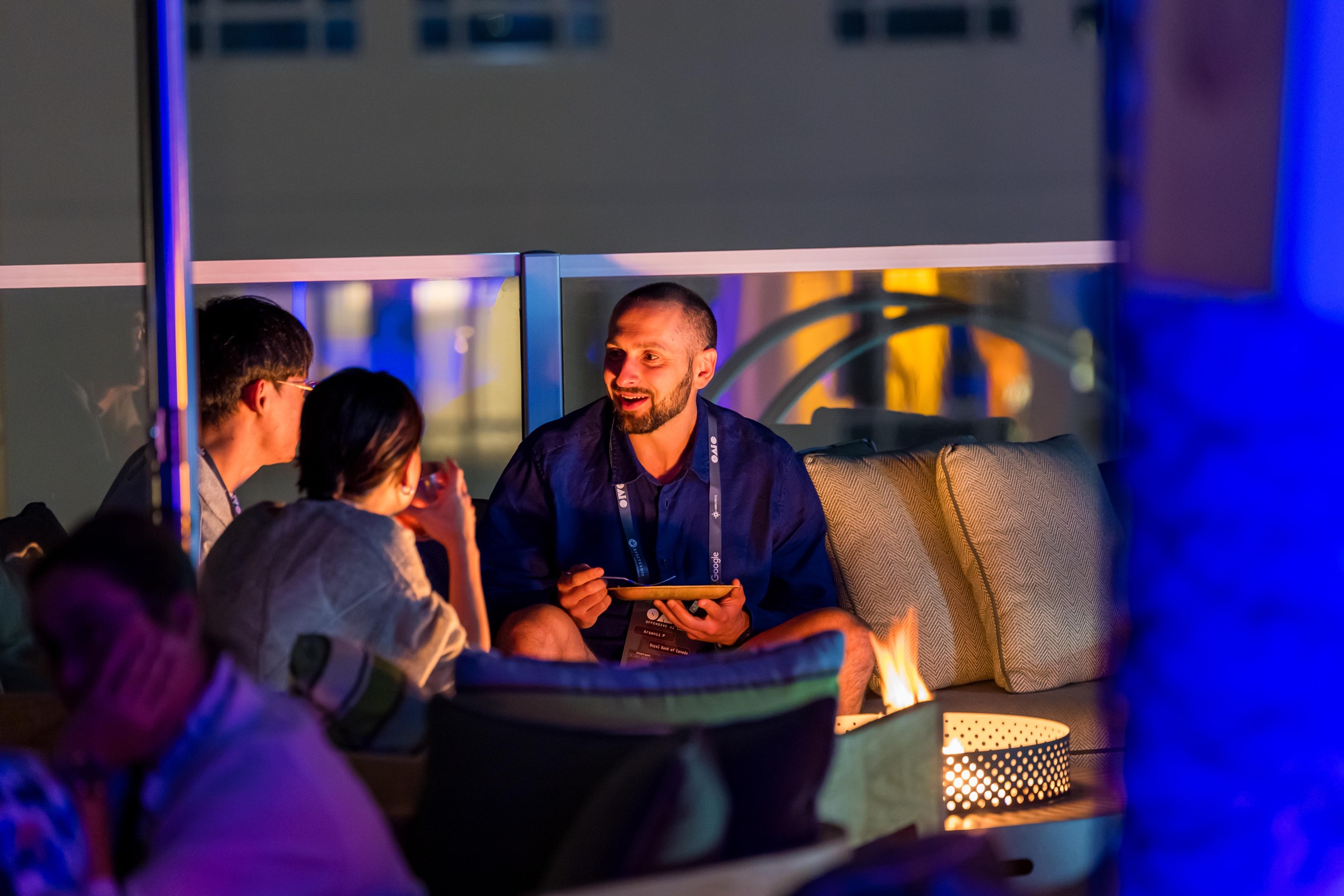 Attendees in conversation in a blue-lit lounge at the Monday gathering.