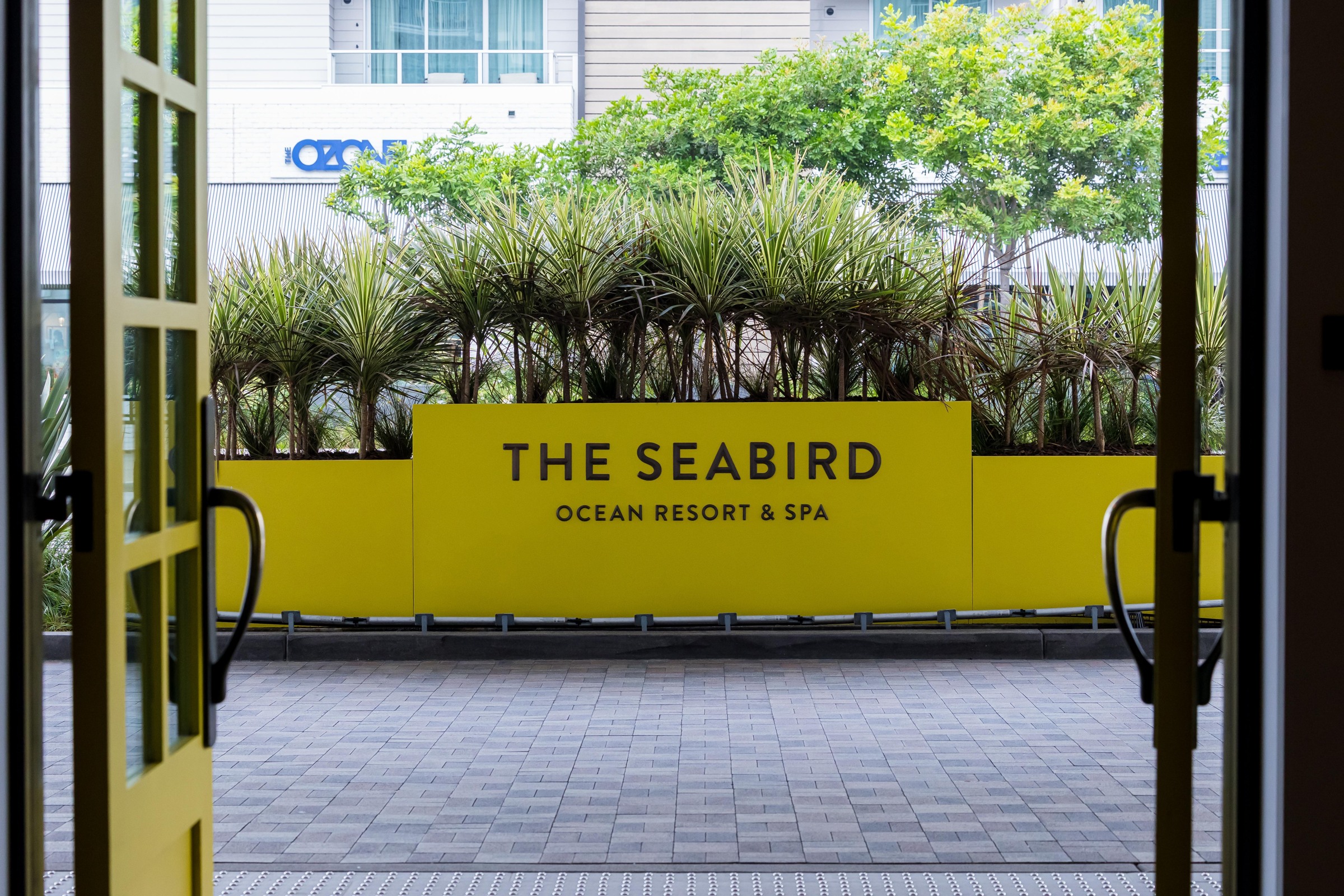 The Seabird resort entrance with its yellow sign and palm planting.