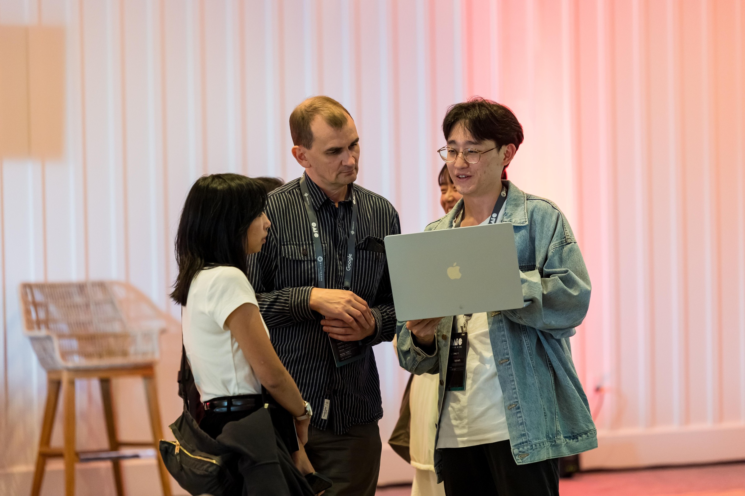 Three attendees reviewing a laptop together between sessions.