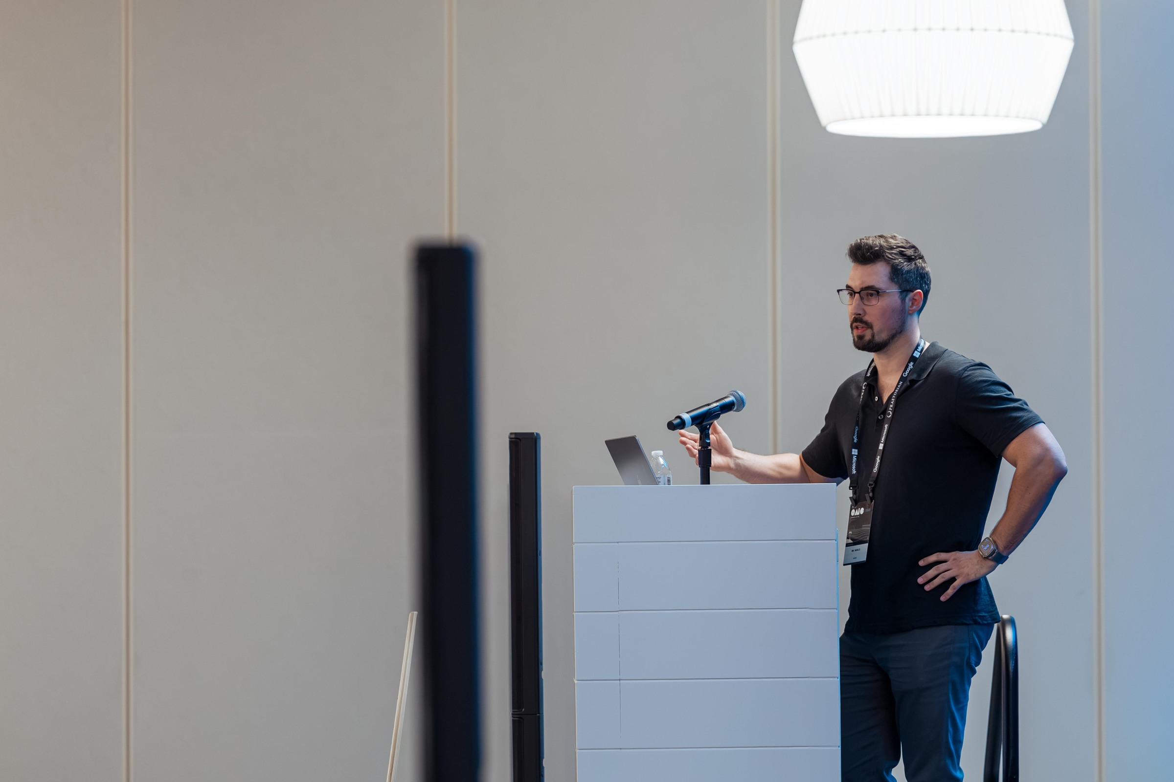 A researcher speaking from the side of the lectern during Deckard: Proving Exploitability.