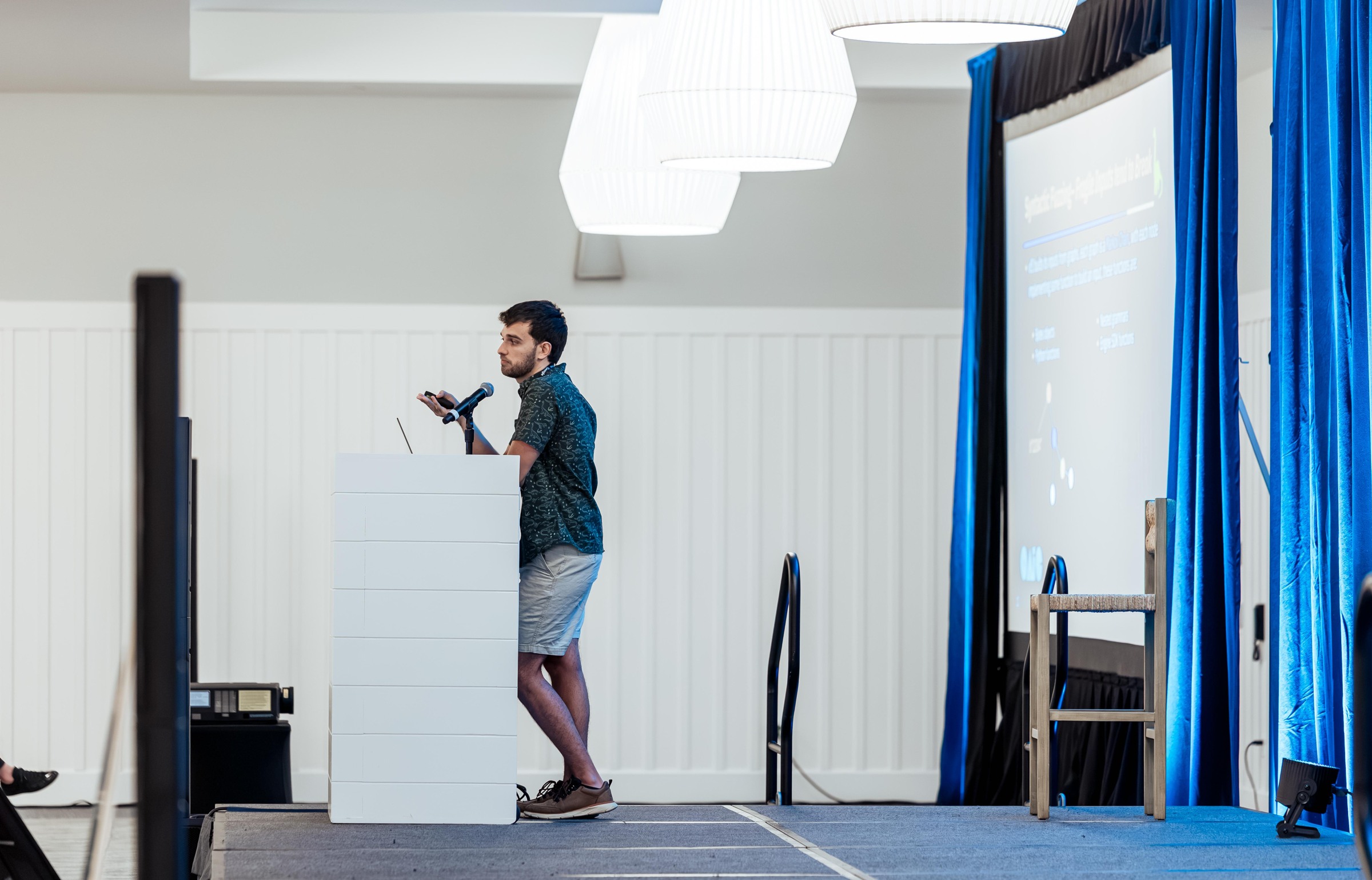 A side view of a researcher presenting Vibe Fuzzing from the conference lectern.