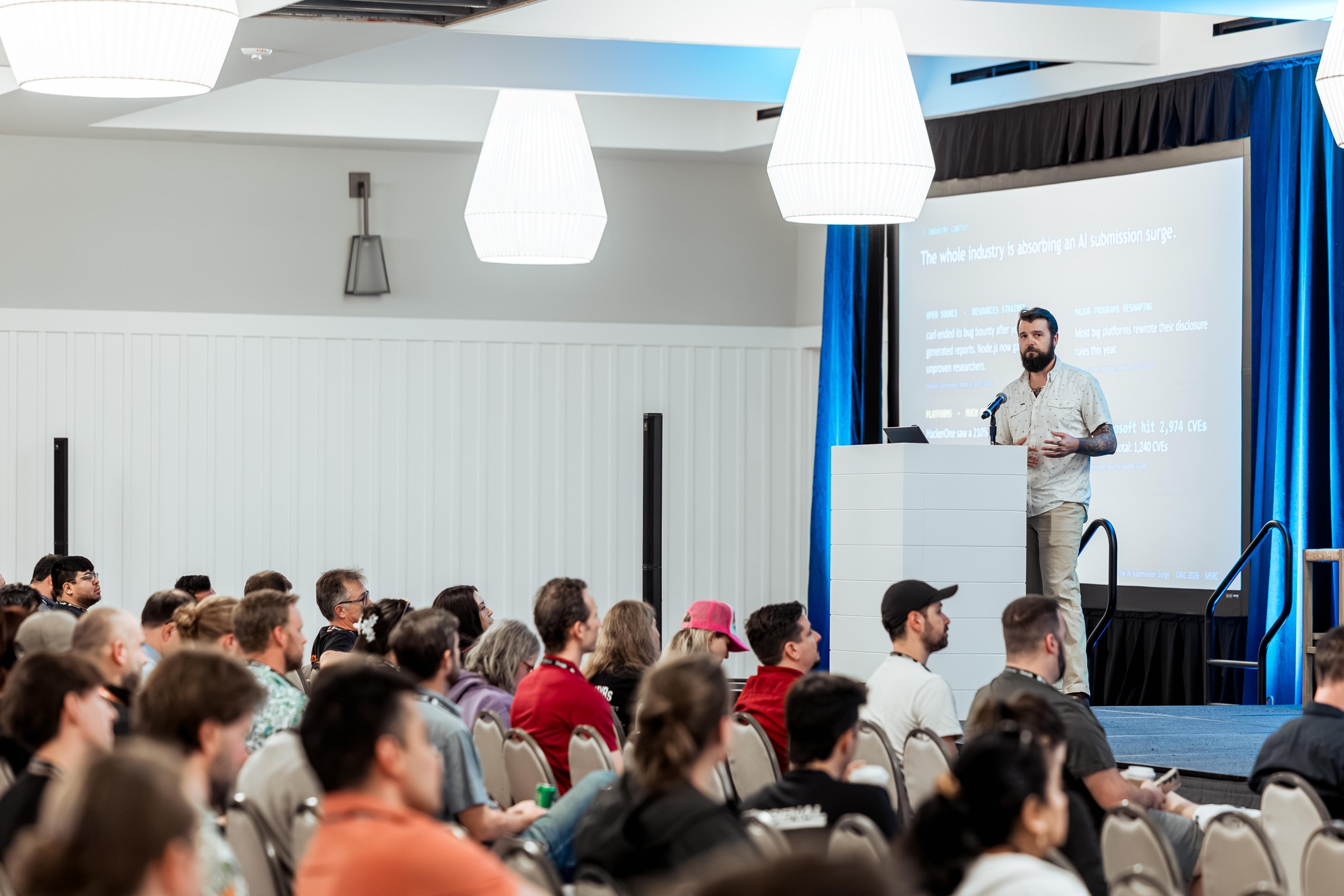 A wide view of the presenter and audience during The AI Submission Surge.
