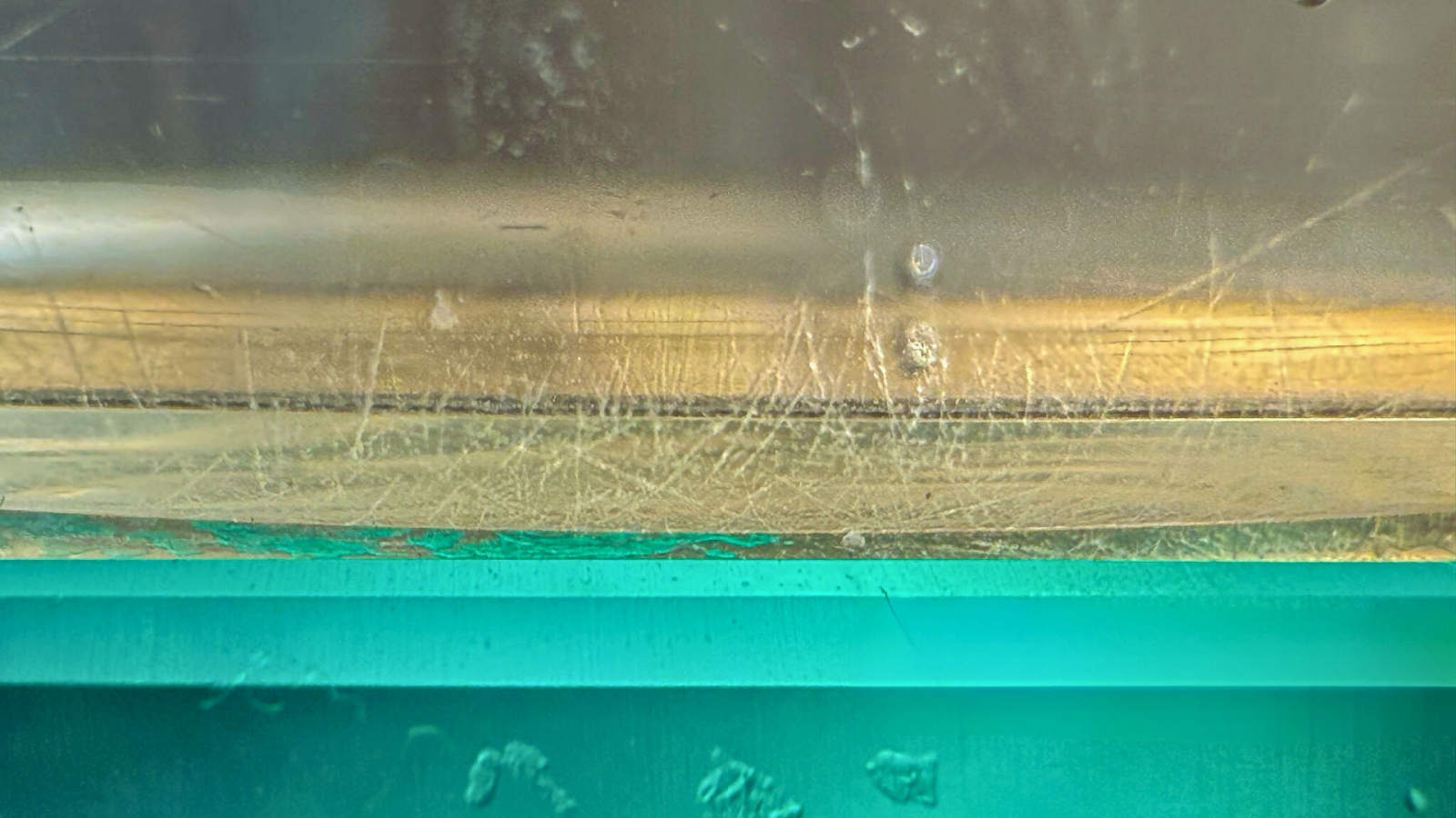 Improper cleaning causing scratches on acrylic pool window.