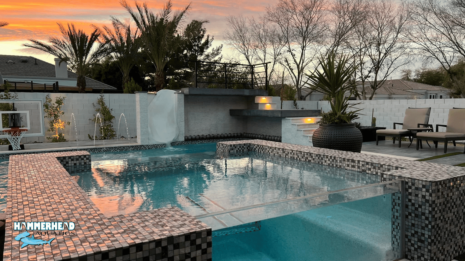 Luxury swimming pool with tile finish and integrated underwater windows at sunset.