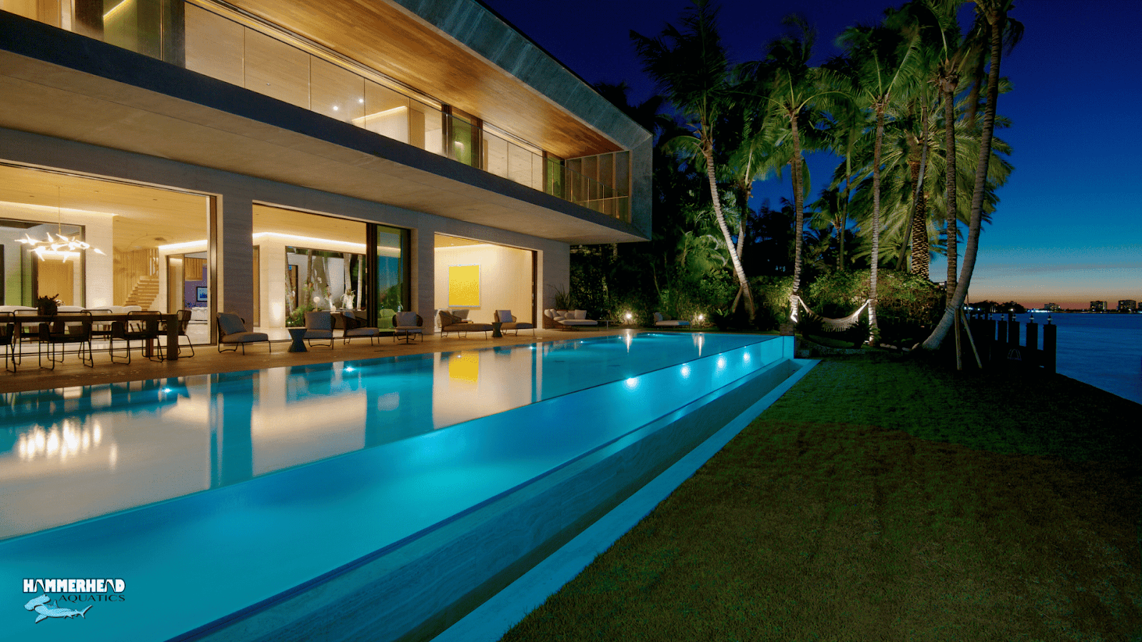 Residential swimming pool with a circular underwater window opening into home gym.