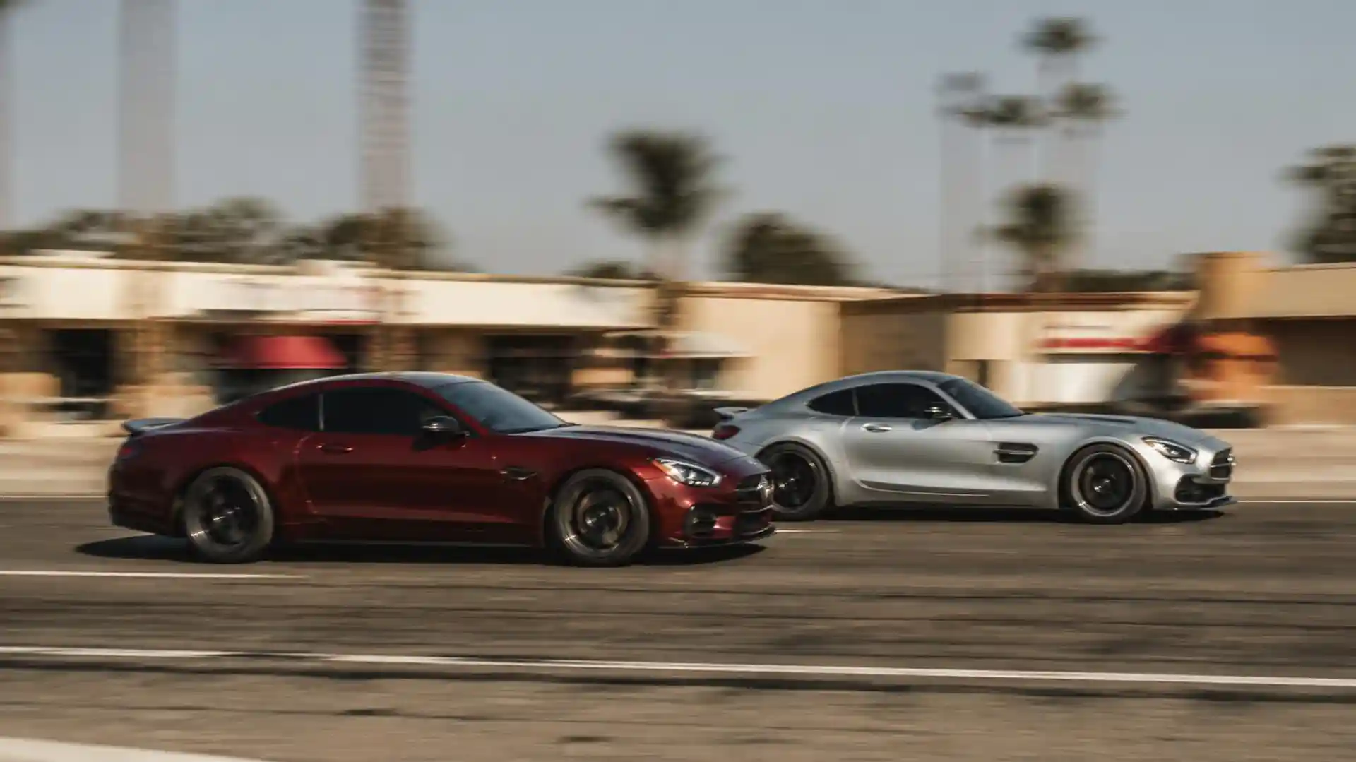 Two sports cars speeding down a sunny street lined with palm trees in Fresno, California