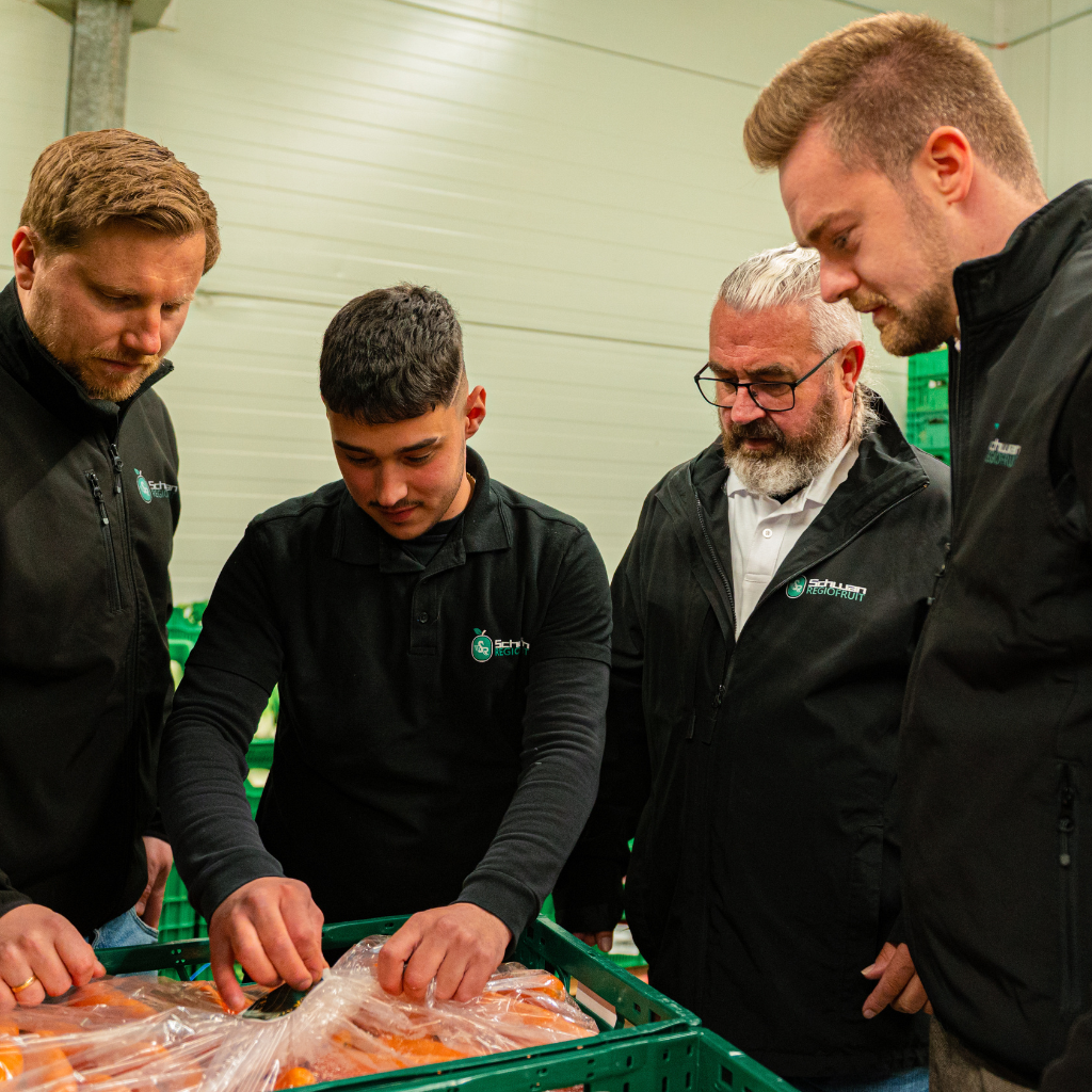 Hendrik Schwan und Kollegen in der Kühlhalle, begutachten Gemüse in einer Gemüsekiste