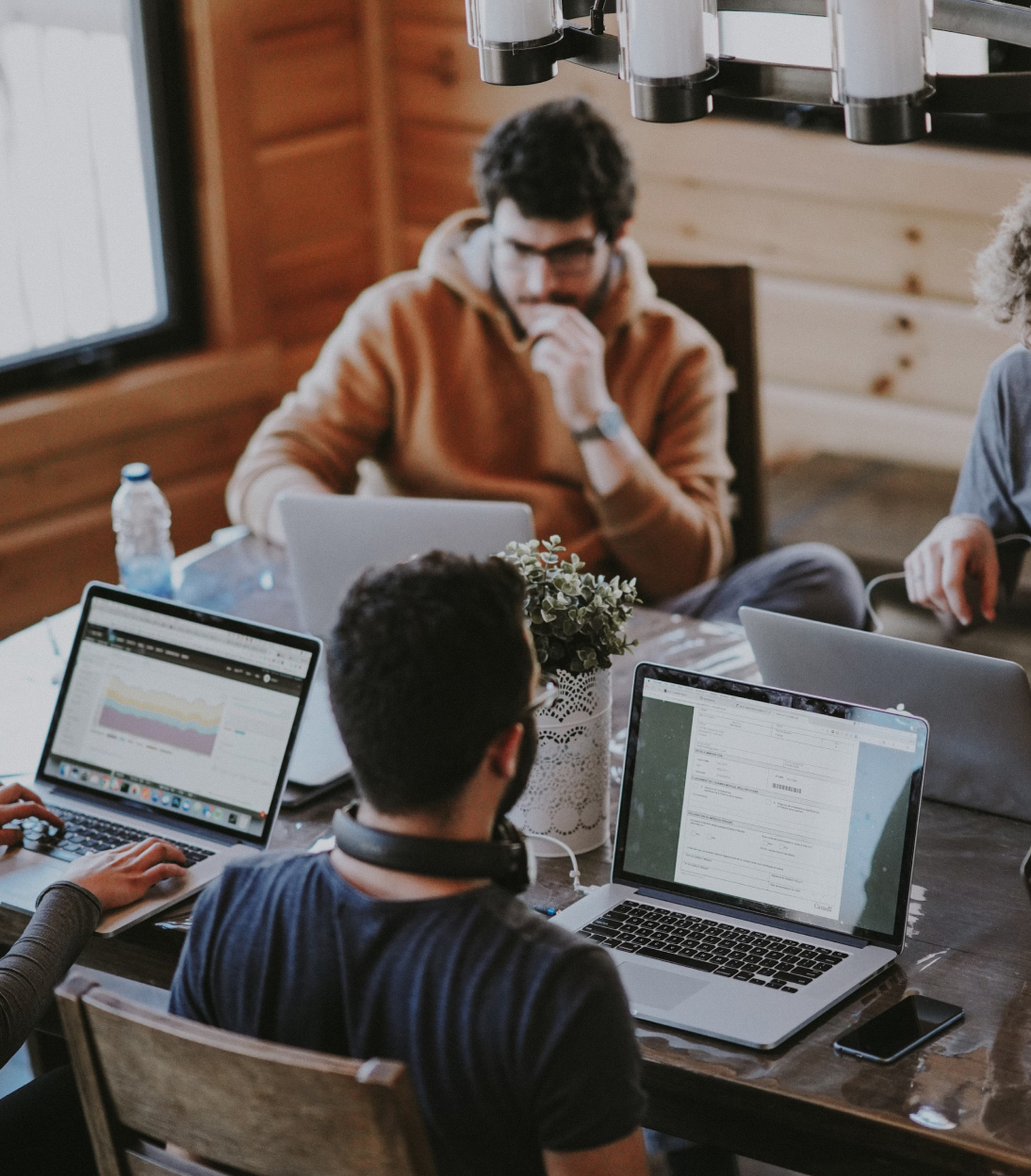 a group of people sitting around a table with laptops