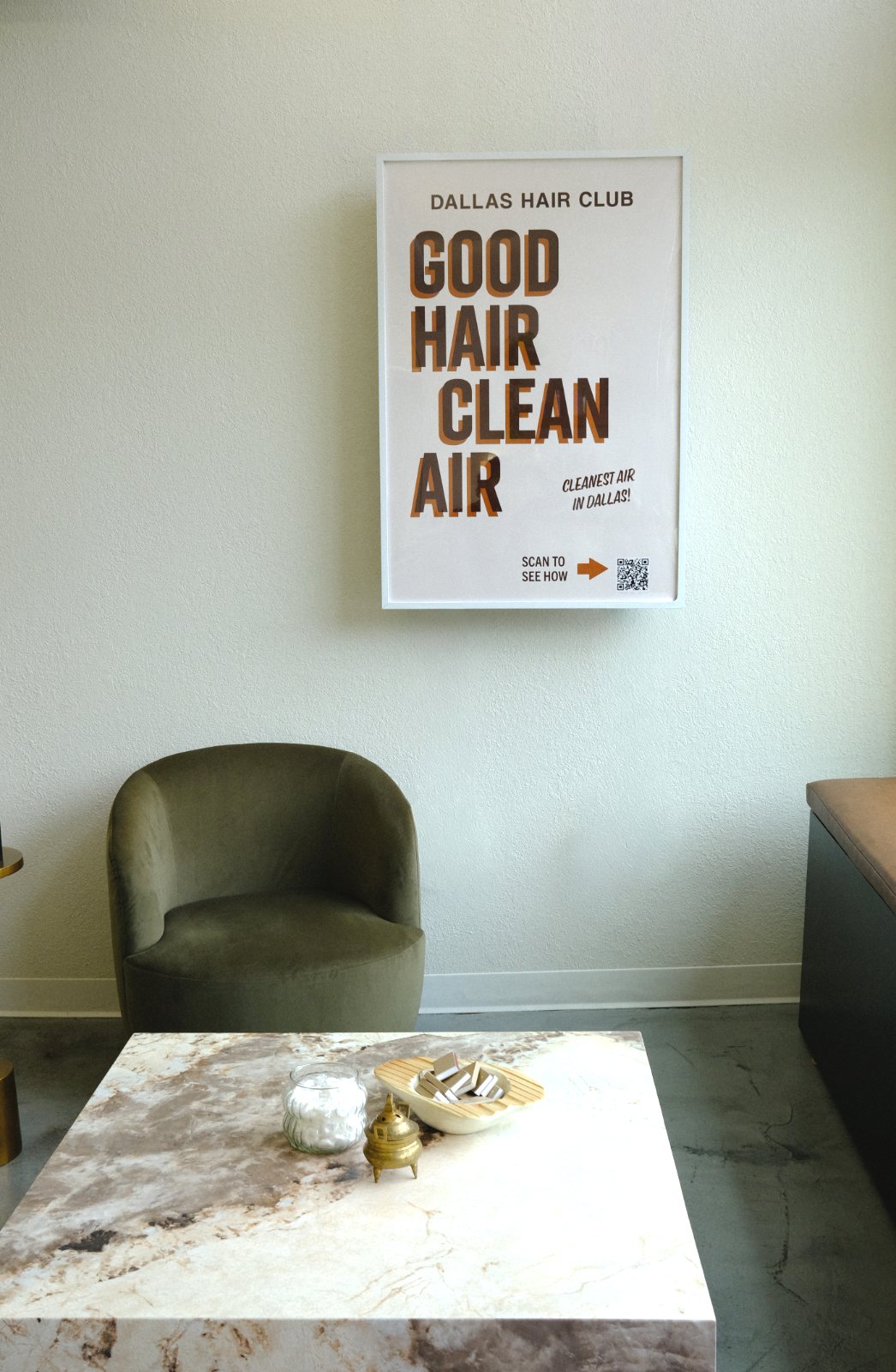 The same lounge wall with a framed 'Good Hair, Clean Air' poster hung over the unit