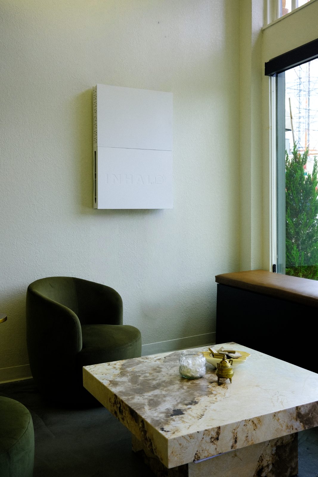INHALO mounted bare on a salon lounge wall, above a green velvet chair and marble table
