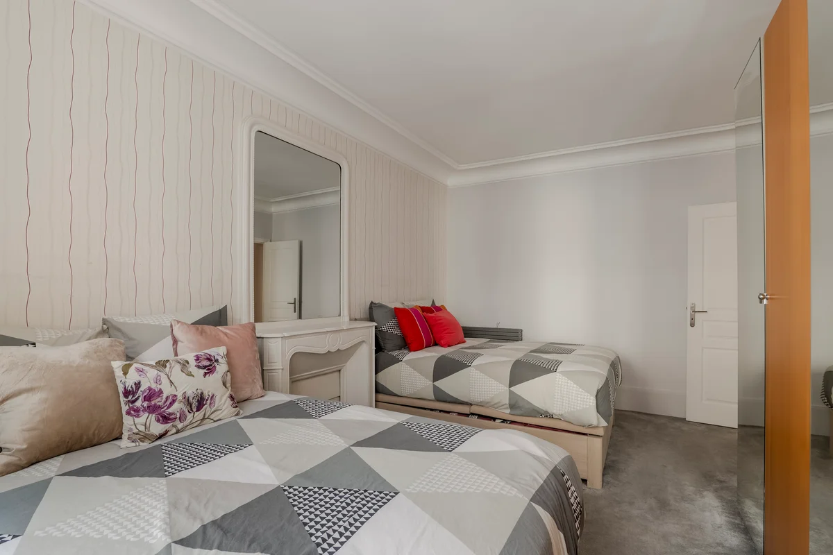 Second angle of the twin bedroom at Casa Cribs with soft linens and warm lighting.