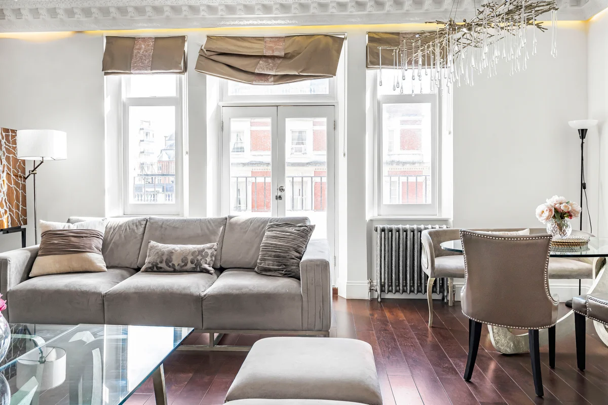 Grand living room at Casa Cribs with high ceilings, ornate chandeliers, and large windows.