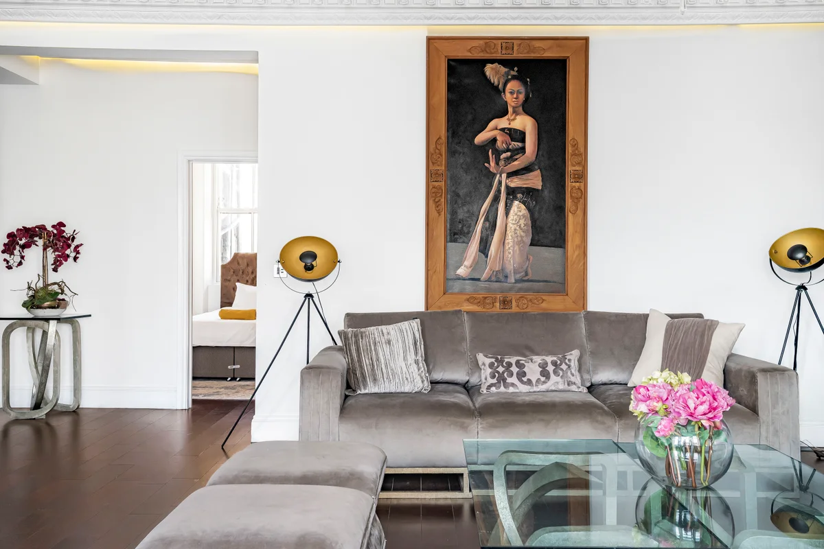 Alternative angle of the living room at Casa Cribs highlighting the portrait of a woman and refined details.